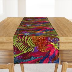 a wooden table topped with a colorfully patterned table runner next to a wood bench