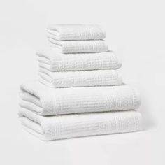 six white towels stacked on top of each other in a stack against a white background