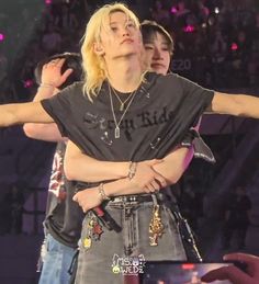 a woman with blonde hair and piercings standing in front of a crowd holding her arms out