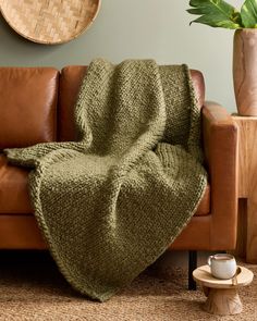 a couch with a green blanket on top of it next to a potted plant