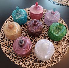 there are many different colored cupcakes on the doily that is sitting on the table