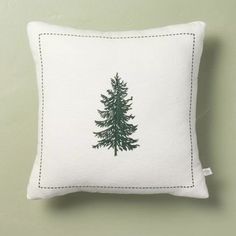 a white pillow with a green pine tree on it