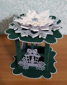 a small green box with white flowers on it's lid sitting on a table