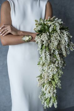 a woman in a white dress holding a bouquet of flowers with her hands on her hip