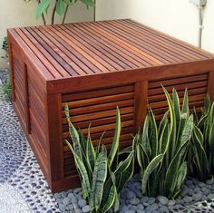 a wooden box sitting on top of a tiled floor next to two potted plants