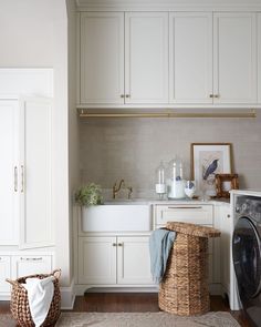 a washer and dryer in a room with white cupboards, cabinets and drawers