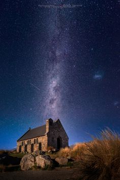 an old church sits on top of a hill under the night sky with stars in the background