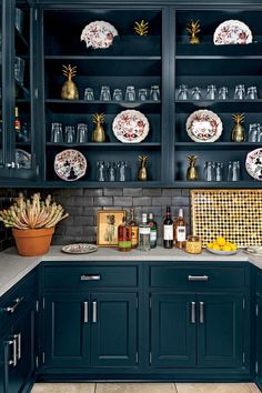 a kitchen with black cabinets and white plates on the counter top, gold trim around the edges