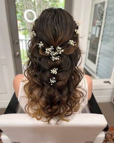 the back of a woman's head with flowers in her hair, sitting at a table