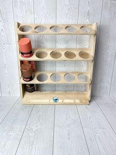 a wooden shelf with spice and condiments on it against a white painted wall