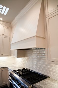 a stove top oven sitting inside of a kitchen next to white cabinets and counter tops