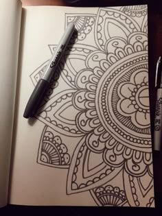 a pen is sitting on top of an open book with a drawing in the background