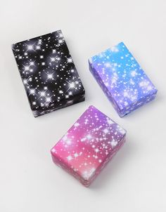 three different colored boxes sitting on top of a white surface with stars all over them