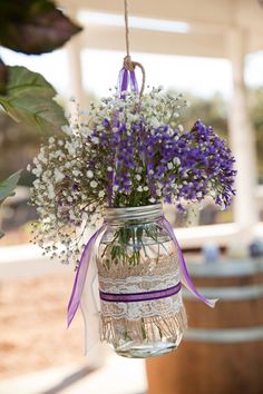 a mason jar filled with purple and white flowers hanging from a ceiling fixture in a house