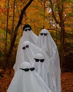 four ghost like figures are standing in the woods with their heads covered by white cloths