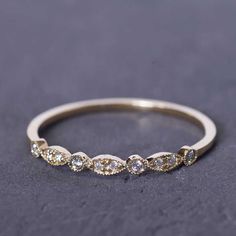 a gold wedding band with five diamonds on it, sitting on a gray surface in front of the camera