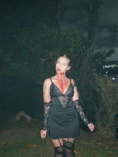 a woman with blood all over her face and body standing in the grass at night