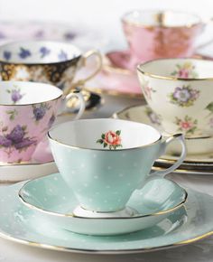 tea cups and saucers with flowers on them are sitting next to each other,