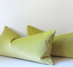 two lime green pillows sitting on top of a white bed