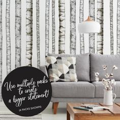 a living room with white and black wallpaper, a grey couch and coffee table