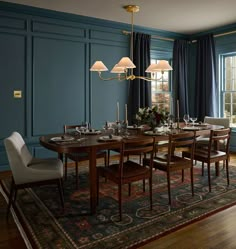 a dining room with blue walls and wooden flooring has a rug on the floor