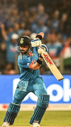 a man holding a cricket bat on top of a field in front of a crowd