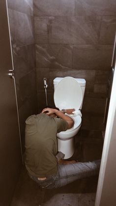 a man squatting down to flush the toilet