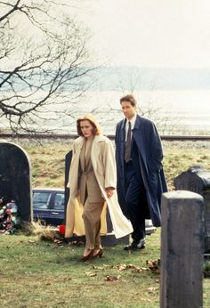 a man and woman walking next to each other in front of a cemetery with headscarves