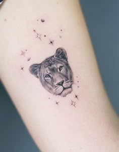 a small tattoo of a lion on the left side of the arm, with stars in the background