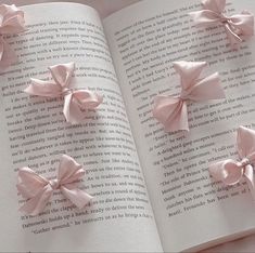 four pink bows on top of an open book