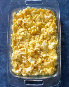 a casserole dish filled with scrambled eggs on a blue tablecloth covered surface