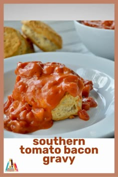 a white plate topped with meat covered in sauce next to biscuits and gravy