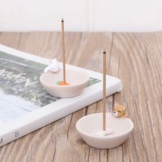 two small bowls with toothpicks in them sitting on a table next to a book