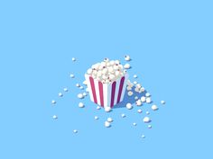 popcorn in a striped paper cup on a blue background with scattered confetti around it