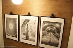 three black and white pictures hanging on a wall next to a lightbulbe