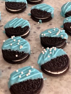 cookies decorated with blue frosting and white sprinkles sitting on a table