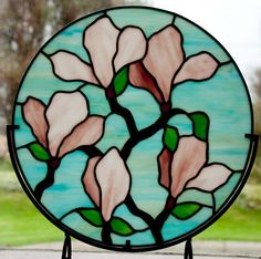 a round stained glass window with pink flowers on the outside and green grass in the background