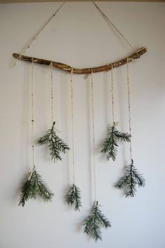 a wall hanging made out of branches and twigs with pine needles attached to the branch