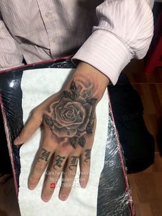 a man's hand with a rose tattoo on it