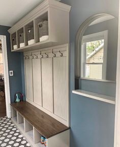 a room with a bench, mirror and coat rack on the wall next to it