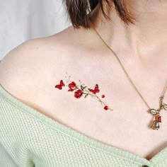 a woman's chest with red flowers on it and a gold chain attached to the chest