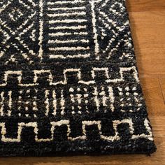 a black and white area rug on the floor with wood floors in the background,