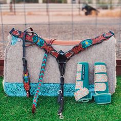 a horse saddle and bridle sitting on the grass in front of a fence