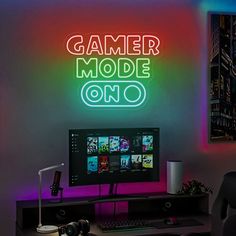 there is a neon sign that says gamer mode one on the wall next to a computer