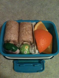 a blue container filled with food on top of a counter next to an orange slice