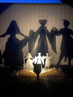 the shadow of three people standing in front of a nativity scene