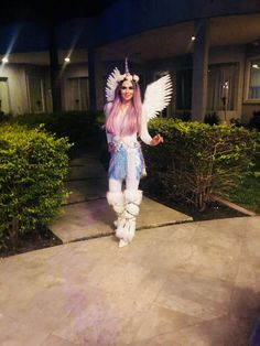 a woman dressed up as an angel standing in front of a house