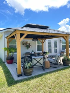 a covered patio with chairs, tables and potted plants on the side of it