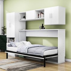 a white bed sitting under a book shelf next to a wall mounted cabinet with drawers