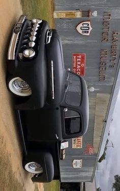 an old black car parked next to a building